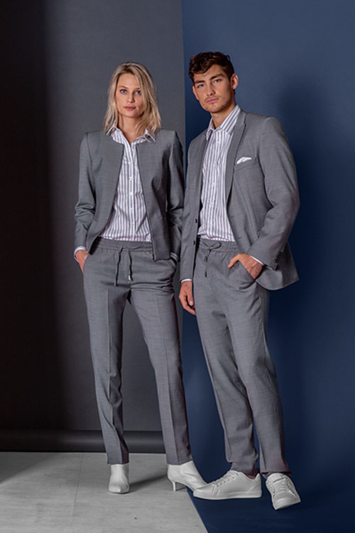Business Athleasure-Wear mit grauem Jacket und Blazer und grauer Business-Schlupfhose mit Gummibund und Bändeln. Dazu ein weiß-grau-gestreiftes Hemd